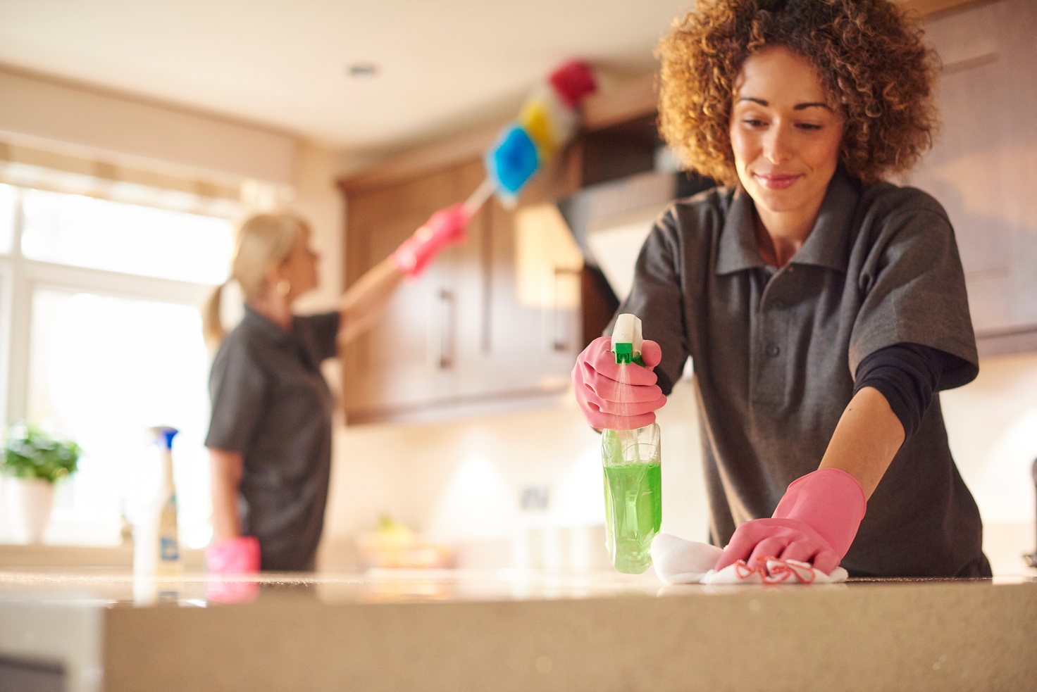 two professional cleaners in a domestic kitchen